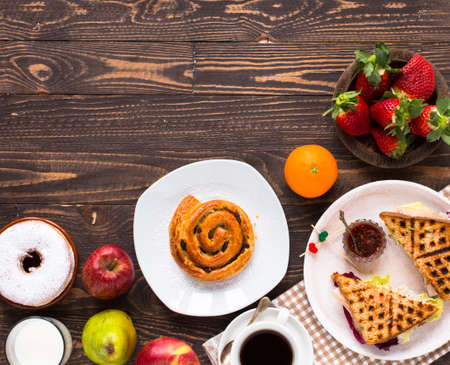 Top view of Healthy Sandwich toast with coffee,donuts, with fruits on a wooden backgroundの写真素材