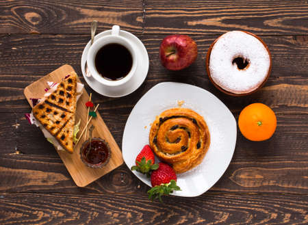 Top view of Healthy Sandwich toast with coffee,donuts, with fruits on a wooden backgroundの写真素材