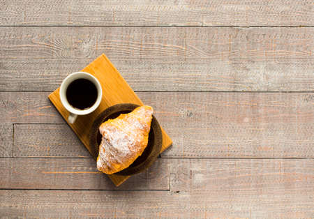 Coffee and croissant for breakfast, on rustic wooden table, top viewの写真素材