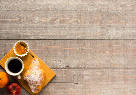 Coffee and croissant for breakfast, on rustic wooden table, top viewの写真素材