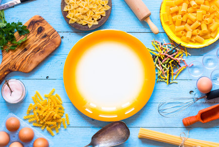 Pasta background. Several types of pasta with vegetables, on a wooden table. Free space for text....