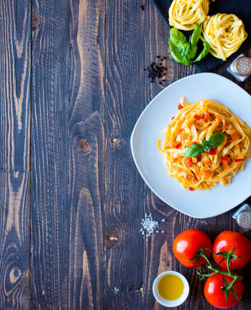 Tagliatelle with tomato and basil, made at home, on a wooden background. Top viewの写真素材