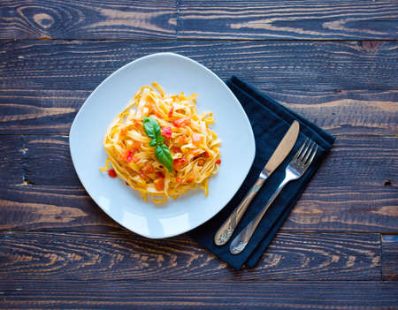 Tagliatelle with tomato and basil, made at home, on a wooden background. Top viewの写真素材