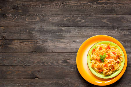 Tagliatelle with tomato and basil, made at home, on a wooden background. Top viewの写真素材