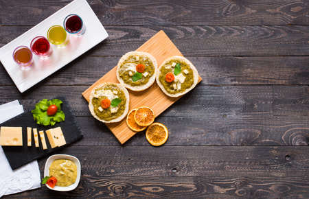 tasty and delicious bruschetta with avocado, tomatoes, cheese, herbs, chips and liquor, on a wooden background. Top viewの写真素材