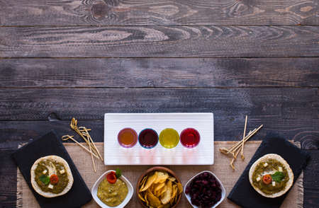 tasty and delicious bruschetta with avocado, tomatoes, cheese, herbs, chips and liquor, on a wooden background. Top viewの写真素材