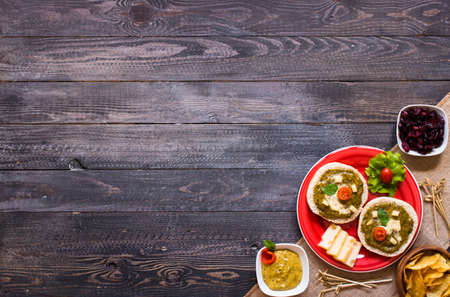 tasty and delicious bruschetta with avocado, tomatoes, cheese, herbs, chips and liquor, on a wooden background. Top viewの写真素材