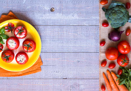 Stuffed tomatoes with cheese, and different vegetables, on a wooden background, free space for text.の写真素材