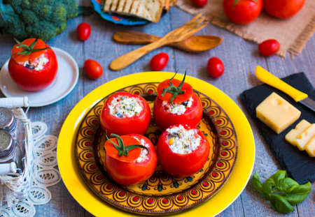 Stuffed tomatoes with cheese, and different vegetables, on a wooden background, free space for text.の写真素材