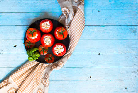 Stuffed tomatoes with cheese, and different vegetables, on a wooden background, free space for text.の写真素材