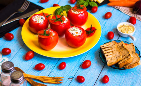 Stuffed tomatoes with cheese, and different vegetables, on a wooden background, free space for text.の写真素材