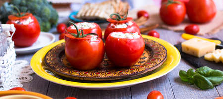 Stuffed tomatoes with cheese, and different vegetables, on a wooden background, free space for text.の写真素材