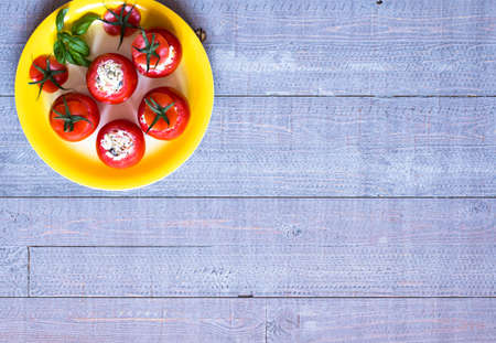 Stuffed tomatoes with cheese, and different vegetables, on a wooden background, free space for text.の写真素材