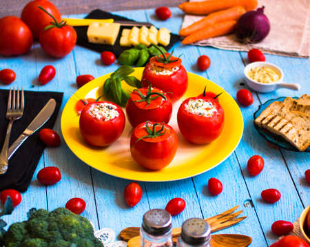 Stuffed tomatoes with cheese, and different vegetables, on a wooden background, free space for text.の写真素材