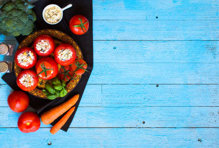 Stuffed tomatoes with cheese, and different vegetables, on a wooden background, free space for text.の写真素材