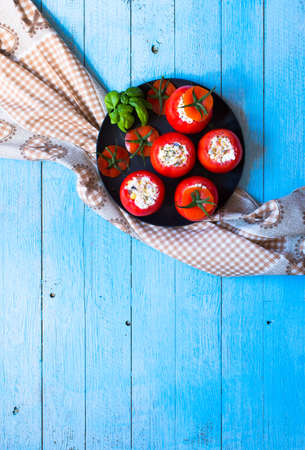Stuffed tomatoes with cheese, and different vegetables, on a wooden background, free space for text.の写真素材