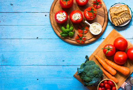 Stuffed tomatoes with cheese, and different vegetables, on a wooden background, free space for text.の写真素材