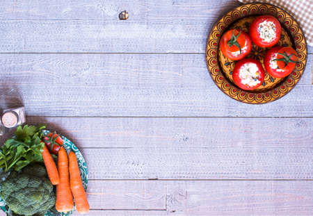Stuffed tomatoes with cheese, and different vegetables, on a wooden background, free space for text.の写真素材