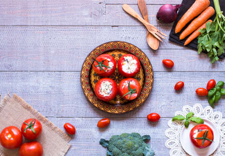 Stuffed tomatoes with cheese, and different vegetables, on a wooden background, free space for text.の写真素材