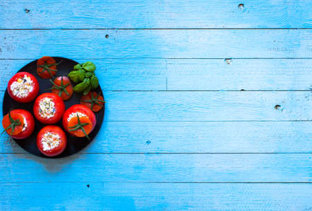 Stuffed tomatoes with cheese, and different vegetables, on a wooden background, free space for text.の写真素材