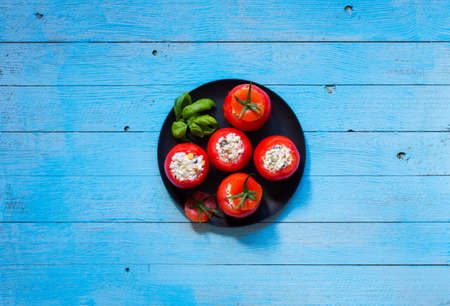 Stuffed tomatoes with cheese, and different vegetables, on a wooden background, free space for text.の写真素材
