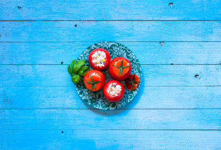 Stuffed tomatoes with cheese, and different vegetables, on a wooden background, free space for text.の写真素材
