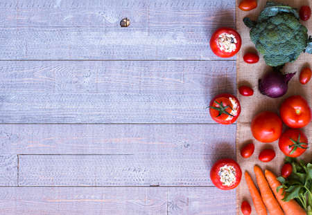 Stuffed tomatoes with cheese, and different vegetables, on a wooden background, free space for text.の写真素材