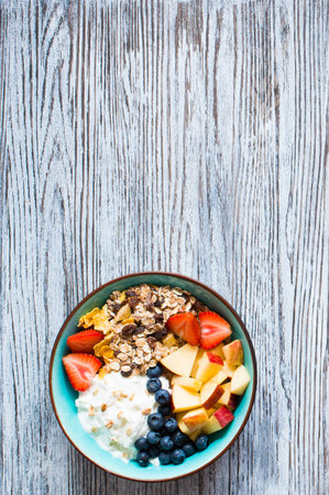 Healthy breakfast, cereal with yogurt, strawberries, blueberry, apple, banana, on wooden rustic...