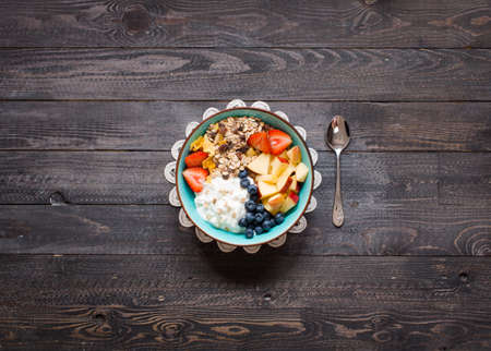 Healthy breakfast, cereal with yogurt, strawberries, blueberry, apple, banana, on wooden rustic background. Top viewの写真素材