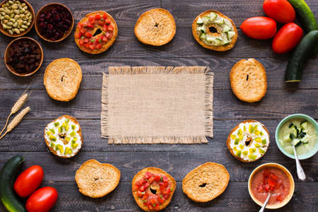 Italian bruschetta with cheese, tomato sauce, cucumber sauce, and herbs, on a wooden background. Top viewの写真素材
