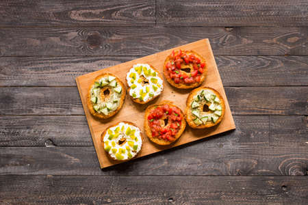 Italian bruschetta with cheese, tomato sauce, cucumber sauce, and herbs, on a wooden background. Top viewの写真素材
