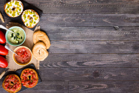 Italian bruschetta with cheese, tomato sauce, cucumber sauce, and herbs, on a wooden background. Top viewの写真素材