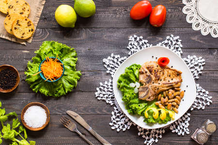 Pork steak homemade cooking with spices leaves lettuce on wooden cutting board, and a dish, on a wooden background,の写真素材