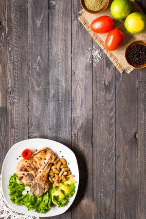Pork steak homemade cooking with spices leaves lettuce on wooden cutting board, and a dish, on a wooden background,の写真素材
