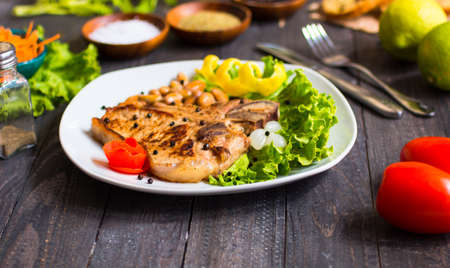 Pork steak homemade cooking with spices leaves lettuce on wooden cutting board, and a dish, on a wooden background,の写真素材