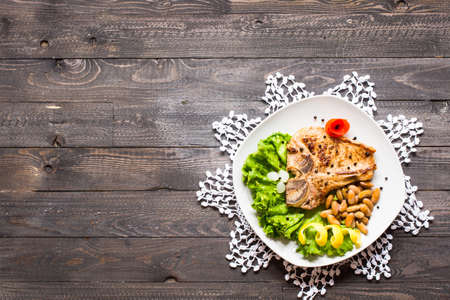 Pork steak homemade cooking with spices leaves lettuce on wooden cutting board, and a dish, on a wooden background,の写真素材