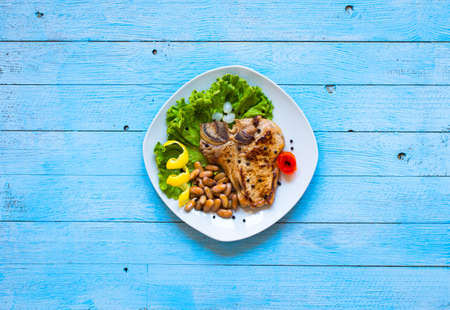 Pork steak homemade cooking with spices leaves lettuce on wooden cutting board, and a dish, on a wooden background,の写真素材