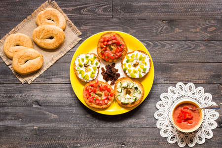 Italian bruschetta with cheese, tomato sauce, cucumber sauce, and herbs, on a wooden background. Top viewの写真素材