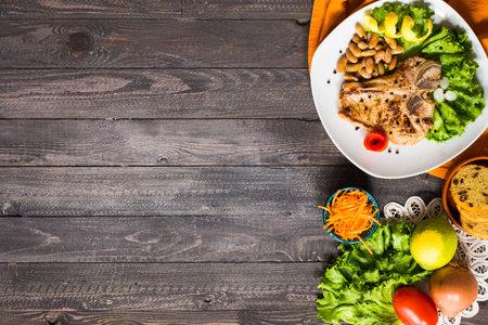 Pork steak homemade cooking with spices leaves lettuce on wooden cutting board, and a dish, on a...