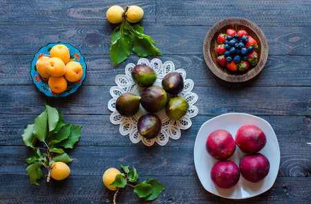 Fresh figs with peaches, apricots, blueberries, strawberries, on a wooden  background. with empty...