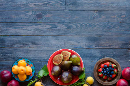Fresh figs with peaches, apricots, blueberries, strawberries, on a wooden  background. with empty copy space close upの写真素材