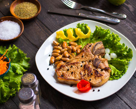 Pork steak homemade cooking with spices leaves lettuce on wooden cutting board, and a dish, on a wooden background,の写真素材