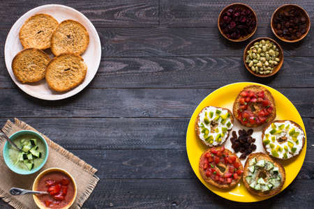 Italian bruschetta with cheese, tomato sauce, cucumber sauce, and herbs, on a wooden background. Top viewの写真素材