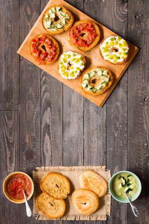 Italian bruschetta with cheese, tomato sauce, cucumber sauce, and herbs, on a wooden background. Top viewの写真素材