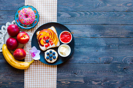 Delicious healthy breakfast, fruit sandwiches with different fillings, cheese, banana, strawberry, fishing, butter, blueberry, on a different wooden background. top viewの写真素材
