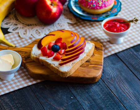 Delicious healthy breakfast, fruit sandwiches with different fillings, cheese, banana, strawberry, fishing, butter, blueberry, on a different wooden background. top viewの写真素材