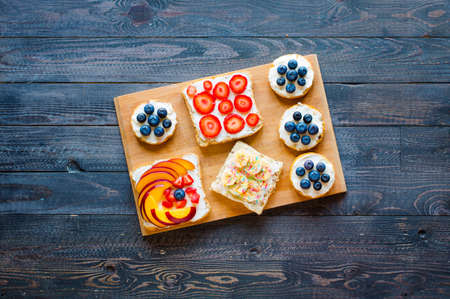 Delicious healthy breakfast, fruit sandwiches with different fillings, cheese, banana, strawberry, fishing, butter, blueberry, on a different wooden background. top viewの写真素材