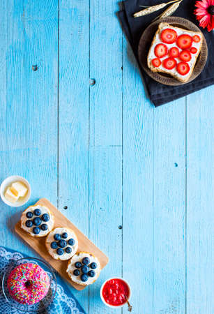 Delicious healthy breakfast, fruit sandwiches with different fillings, cheese, banana, strawberry, fishing, butter, blueberry, on a different wooden background. top viewの写真素材