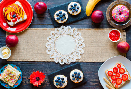 Delicious healthy breakfast, fruit sandwiches with different fillings, cheese, banana, strawberry, fishing, butter, blueberry, on a different wooden background. top viewの写真素材