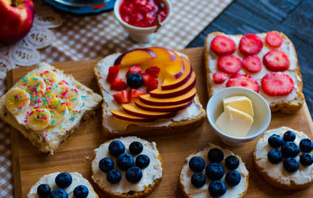 Delicious healthy breakfast, fruit sandwiches with different fillings, cheese, banana, strawberry, fishing, butter, blueberry, on a different wooden background. top viewの写真素材